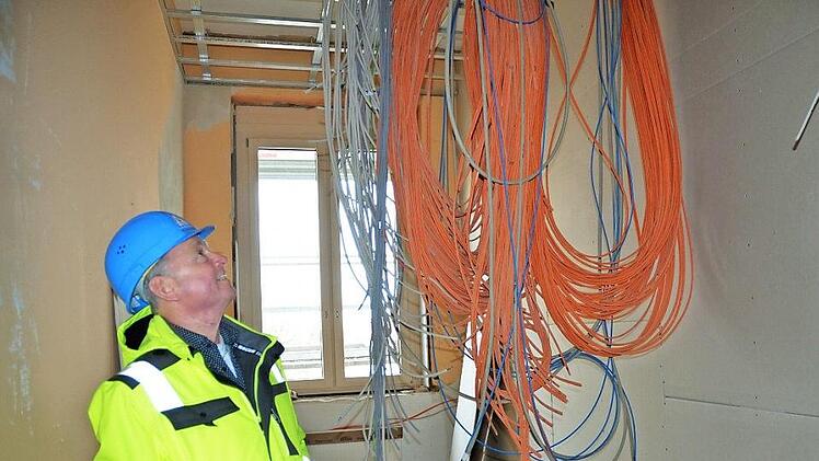 Stadtratsmitglied Heinz Pommer betrachtet die Kabel, die im künftigen Server-Raum der Mittelschule von der Decke hängen. Foto: Rainer Lutz