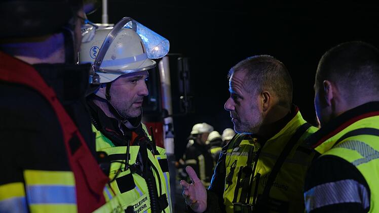 Der Murnauer Arzt Dr. Bender (links) bespricht sich mit einem Feuerwehrmann am Unfallort.