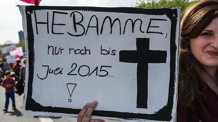 Eine Frau trägt am 12.04.2014 in Berlin bei einem Protestumzug für den Erhalt der freien Geburtenhilfe ein Plakat. Nach Angaben der Polizei nahmen schätzungsweise 2000 Menschen an einer Demonstration gegen die geplante Erhöhung der Versicherungsprämien für freiberufliche Hebammen teil. Foto: Paul Zinken/dpa