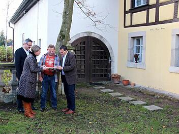 Kerstin Blum und Bürgermeister Fischkal schauen mit Siggi Kraus das Geschenk (Adelsdorf Chronik) an, dahinter links Wolfgang Mößlein - im Hintergrund die Scheune  Fotos: Johanna Blum