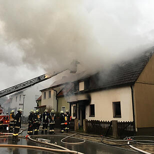 Brand in Doppelhaushälfte: Anderer Gebäudeteil in Mitleidenschaft gezogen - Bewohner verletzt – Feuerwehr muss Dachstuhl öffnen um Glutnester zu bekämpfen