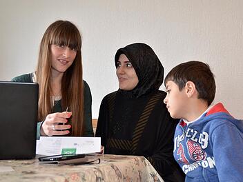 Lucia Schmitt (links) betreut seit Februar die Flüchtlinge in den Unterkünften Stangenroth und Waldfenster. Hier klärt die Sozialpädagogin Fragen mit der Syrerin Aya und ihrem achtjähriger Sohn Mahmut, die in Stangenroth untergebracht sind. Schmitts Vorgängerin Veronika Richler arbeitet inzwischen in einem Flüchtlingscamp in Jordanien. Foto;: Kathrin Kupka-Hahn