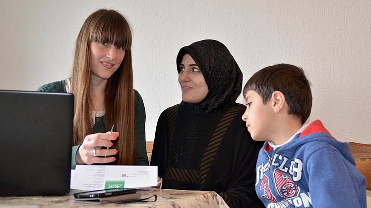 Lucia Schmitt (links) betreut seit Februar die Flüchtlinge in den Unterkünften Stangenroth und Waldfenster. Hier klärt die Sozialpädagogin Fragen mit der Syrerin Aya und ihrem achtjähriger Sohn Mahmut, die in Stangenroth untergebracht sind. Schmitts Vorgängerin Veronika Richler arbeitet inzwischen in einem Flüchtlingscamp in Jordanien. Foto;: Kathrin Kupka-Hahn