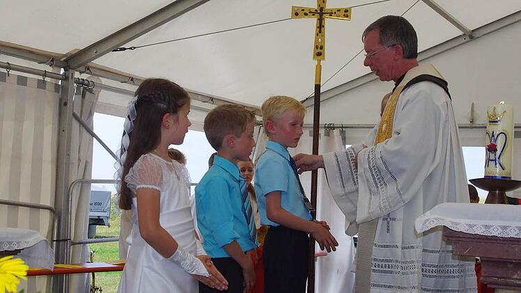 Die diesjährigen Kommunionkinder (von links) Anna, Julian und Sven ließen sich von Karmelitenpater Roland Hinzer in die Skapulierbruderschaft aufnehmen. Foto: Heike Schülein