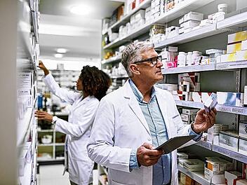 Stocking up. Shot of two focused pharmacist walking around and doing stock inside of a pharmacy.