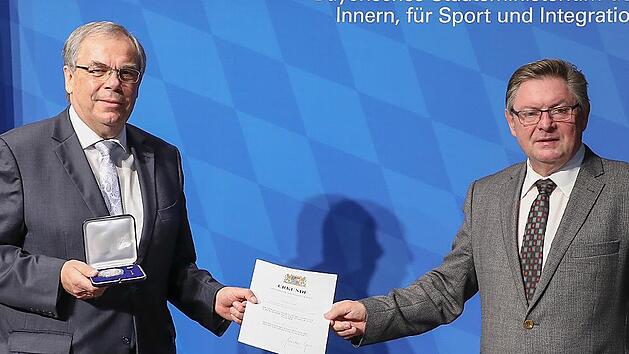 Gerhard Eck (rechts) &uuml;bergibt Bernhard Ru&szlig; die Verdienstmedaille und eine Urkunde.