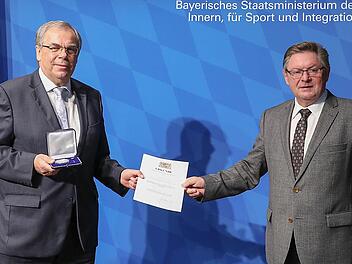 Gerhard Eck (rechts) übergibt Bernhard Ruß die Verdienstmedaille und eine Urkunde.