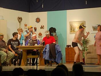 Opa Holzmeier (Eugen Katzenberger) und sein Enkel Markus (Stefan Schmitt) sowie Amanda (Melanie Reininger), Franziska Gierig (Christiane Wendel), August (Hubert Heinickel) und Franz-Josef (Frank Dünisch) haben ihren Spaß, dass der strippende Postbote Ferdinand (Fritz Braun) von seiner Ehefrau Paula (Doris Beck) zusammengestaucht wird. Foto: Manfred Mellenthin