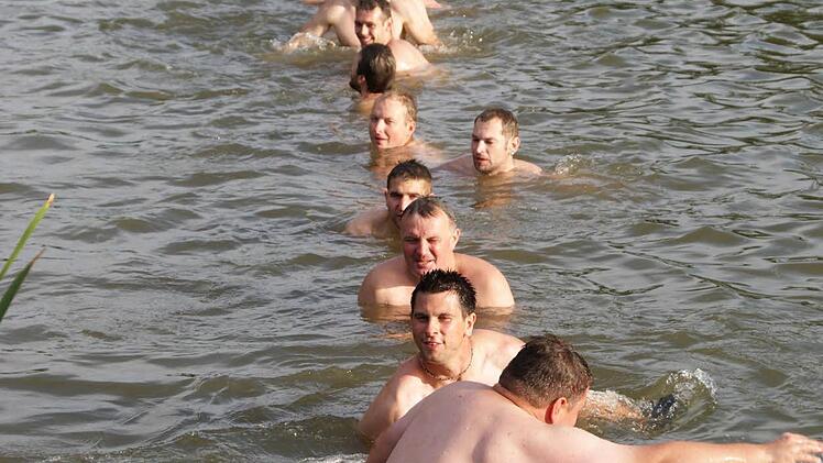 Die Kerwasburschen nach dem Baumaufstellen in der Aisch, sitzend auf dem Stamm der vorjährigen Fichte - die ist dabei wohl etwas unter Wasser gedrückt worden. Aber alle haben darauf Platz gefunden.