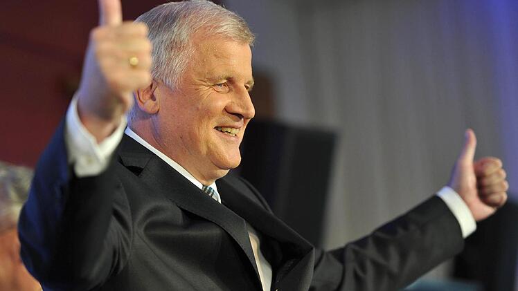Der bayerische Ministerpräsident und CSU-Vorsitzende Horst Seehofer steht in München nach der Bekanntgabe der Hochrechnungen zur Landtagswahl in Bayern mit hochgestreckten Daumen auf dem Podium. Foto: Inga Kjer/dpa
