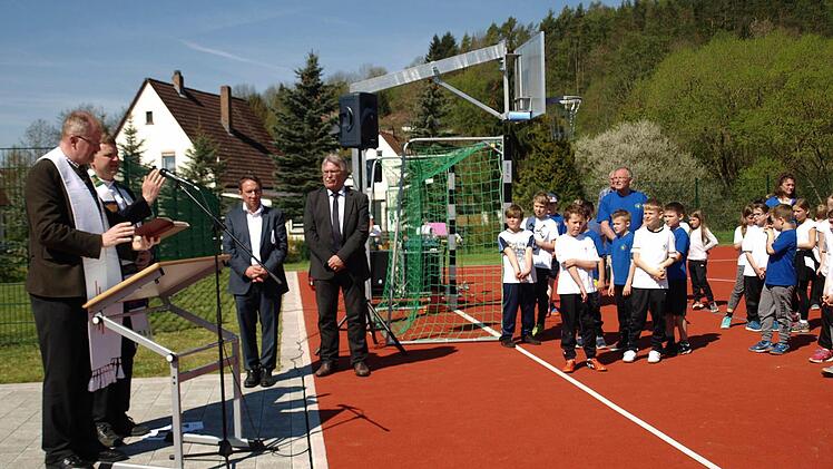 Regionaldekan Thomas Teuchgräber segnet die Außensportanlagen mit Weihwasser. Ganz links Pfarrer Andreas Krauter. Foto: Susanne Deuerling