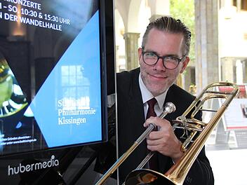Posaunist Roman Riedel an einer Werbesäule, die auf den neuen Namen des Kurorchesters hinweist. Benedikt Borst