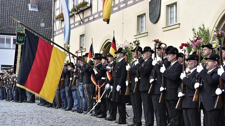 Die Bürgerwehr ist angetreten vor dem Rathaus: Es geht den Teilnehmern am Auszug unter die Haut, wenn sich die Bürgerwehrfahne zum Lied vom Kameraden senkt. Die Blumen an den Gewehren oder Spazierstücken sollen den friedlichen Charakter der Aktion dokumentieren.
