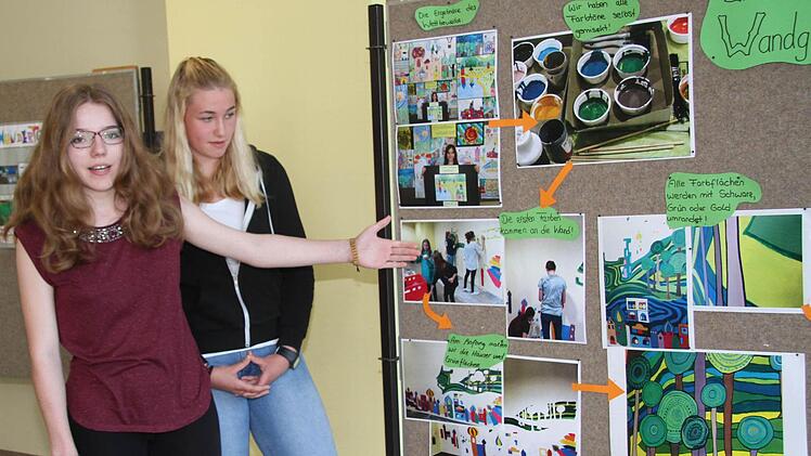Sarah Schilge (15) und Pauline Schweens (15) zeigen, wie das riesige Gemälde entstanden ist. Am Anfang wurde an der Realschule ein Malwettbewerb durchgeführt, aus den einzelnen Bildern wurden dann Elemente herausgenommen. Foto: Sonny Adam