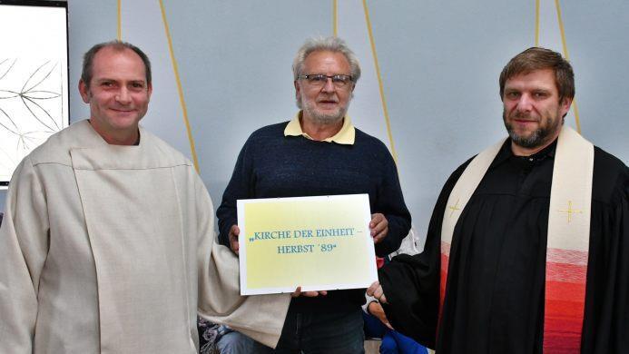 Ralf Luther, Vorsitzender des Vereins Autobahnkirche Bibra A 71 bei der offiziellen Namensgebung der Kirche. Symbolisch überreichte er die kleine Tafel an den evangelischen Pfarrer Michael Schlauraff (Bibra) und Pastoralreferent Ulrich Emge (Mellrichstadt). Foto: Hanns Friedrich
