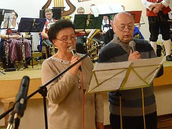 Brigitte Büttner und Norbert Fehn und die "lustigen Musikanten" der Blaskapelle Buchbach (im Hintergrund) unter Leitung von Horst Büttner eröffneten das Wirtshaussingen in Buchbach.  Foto: Karl-Heinz Hofmann