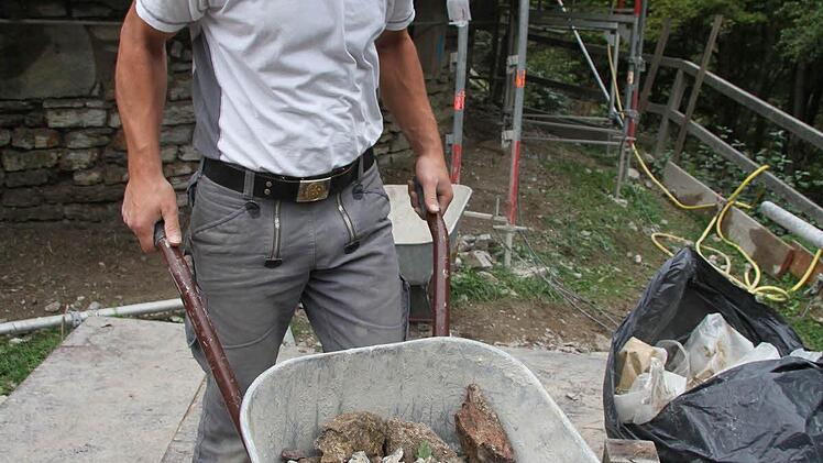 Daniel Böhm kippt die alten, nicht mehr brauchbaren Steine über eine Röhre in die Tiefe - die Baustelle ist schwierig.