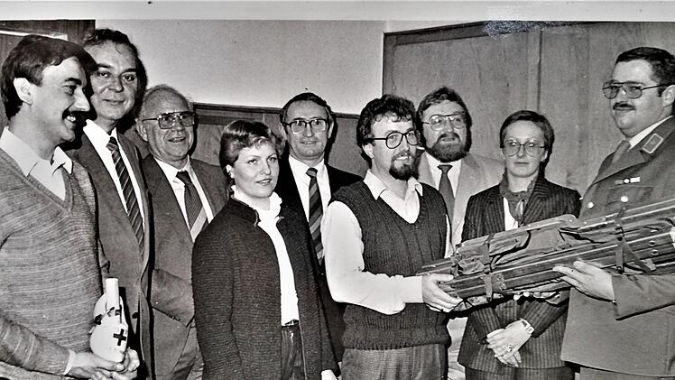 Kreiskolonnenführer Gerhard Glöckler (rechts) überreichte Zugführer Alois Gundalach (vierter von rechts) ein erstes Ausrüstungsstück; mit dabei waren (von links) Hans Huber (stellvertretender Zugführer), Landrat Marko Dyga, Pfarrer Hugo Link, Irene Gundalach (stellv. Bereitschaftschaftsleiterin), Bürgermeister Helmut Schuck, Zugarzt Thomas Stößel und Bereitschaftsleiterin Petra Limpert. Repro: Sigismund von Dobschütz
