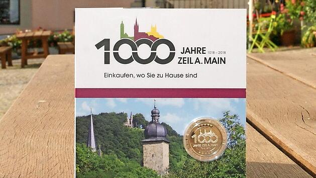 Die Jubil&auml;umsm&uuml;nze ist eingebettet in eine Klappkarte mit Zeiler Motiven und im Design der 1000-Jahr-Feier gestaltet.  Foto: Sabine Weinbeer
