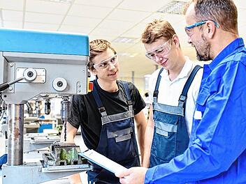 trainer and apprentice in technical vocational training at a drilling machine