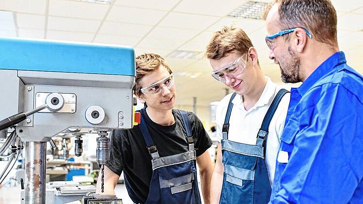 trainer and apprentice in technical vocational training at a drilling machine