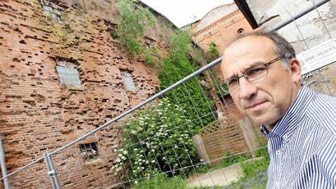 Kreisbaumeister Stefan Weisser steht vor der Wand, aus der es grünt - und von der ein Teil schon eingestürzt ist.