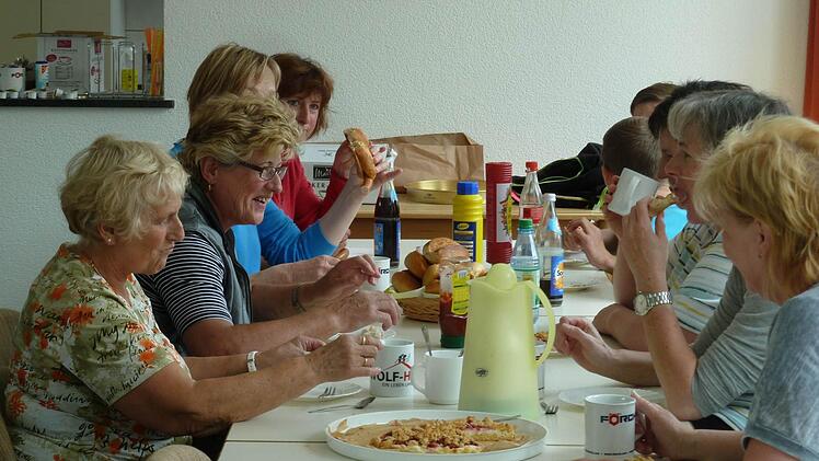 Stralsbacher Frauen bei der Mittagspause:Die geschafften Männer und Frauen ruhen sich gerade leicht ermattet aus bei einer Brotzeit, die Monika Knauer in der neuen Teeküche der nun generalstabsmäßig sanierten "Alten Schuel" organisiert hat. "Ich glaube, uns allen ist etwas Gutes gelungen." Nur die putzenden Frauen dürfen sich über einen köstlichen Kuchen von Ingrid Kröckel hermachen. )