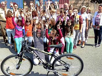 La Ola für ein neues Fahrrad. Im Bild (hinten, von links) Verkehrserzieher Hermann Dörfler, Anka Lubiato, Rosi Müller (Kiwanis), Verkehrserzieher Peter Schütz (verdeckt), Martin und Barbara Wohlfahrt, Bernt Pingel, Annegret Pachner, Doris Rötche (Kiwanis), Schulsekretärin Gisela Pingel und Rektorin Marion Hoffmann. Foto: Dieter Hübner