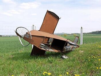 Ein Modell eines abgestürzten Flugzeugs, das von Gegnern des Flugplatzneubaus gebaut wurde, liegt auf einer Wiese nahe dem geplanten Standort für den neuen Verkehrslandeplatz. Foto: Berthold Köhler