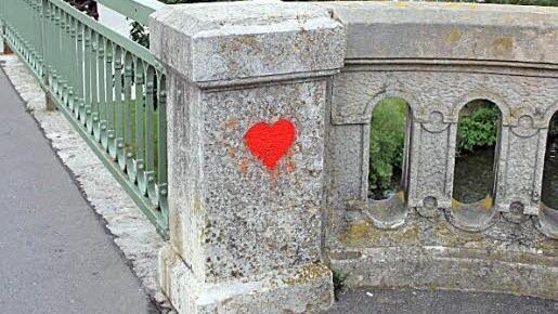 Ein rotes Herz leuchtet an der Brückenmauer.