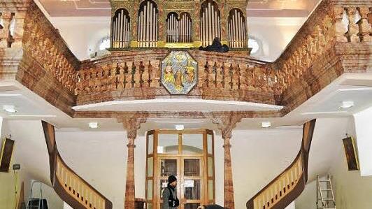 Die Orgelempore mit der farblichen Neufassung des Deckenstucks und der Wandfarbe sowie die Leuchten.