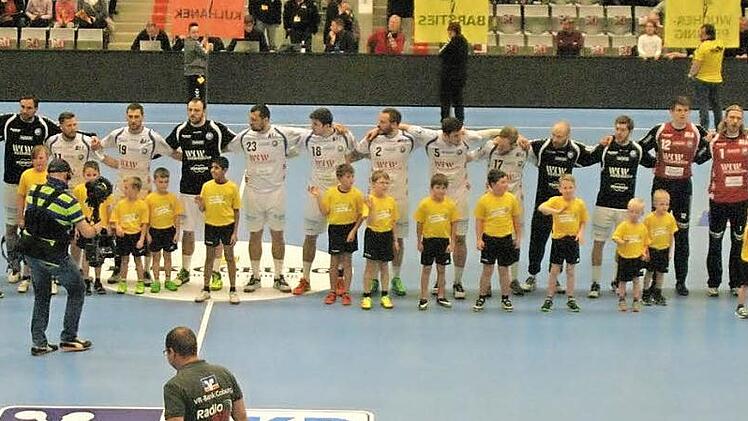 Kurz vor dem Anpfiff steht ein Teil der Windheimer Nachwuchsfu&szlig;baller mit den Spielern des Bergischen HC auf dem Feld. Foto: Iris Bilek