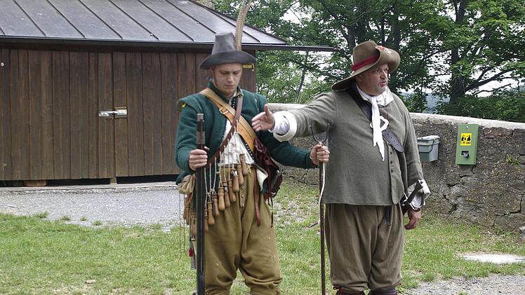 Hauptman Uwe Klotz (rechts) erläutert den Besuchern die Ausrüstung eines Musketiers. Foto: Winfried Ehling
