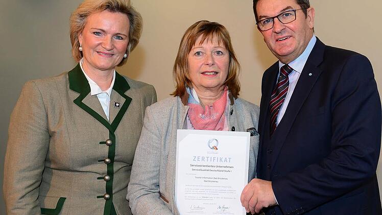 Die Pr&auml;sidentin des Bayerischen Hotel- und Gastst&auml;ttenverbandes Dehoga Bayern, Angela Inselkammer (links), und Wirtschafts- und Tourismusstaatssekret&auml;r Franz Josef Pschierer &uuml;bergaben Karin Bauer von der Tourist-Information Bad Br&uuml;ckenau das Zertifikat.  Foto: Irmi Gessner
