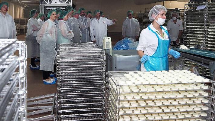 Hygiene ist bei der K&auml;seproduktion oberstes Gebot. Die Wirtschaftsjunioren der IHK zu Coburg waren deshalb mit Haube, Kittel und Schuh&uuml;berziehern versehen. Direktor Ludwig Wei&szlig; (Bildmitte) erl&auml;utert die Verfahrensschritte.  Fotos: Christoph Winter