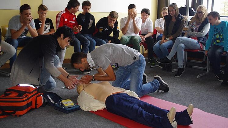 Claudia Simon zeigt Felix Mayerhöfer, Lehrer der Klasse 8 b, wie eine Mund-zu-Mund-Beatmung funktioniert. Foto: Schülein