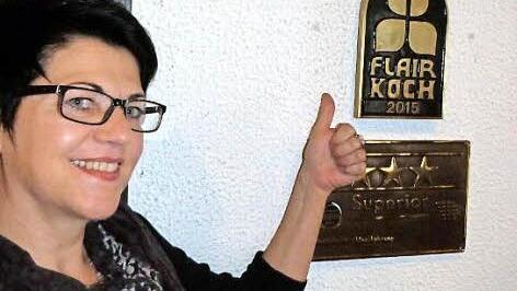 Hotelfachfrau Marion Passing zeigt mit Stolz auf die Flair-Plakette.