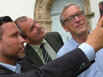 So funktioniert es: Mit dem Smartphone an der jeweiligen Station den Code eingeben und schon laufen hörbar und bildlich die Informationen, wie (von links) Martin Finzel, Rainer Maier und Rolf Gorny es vor der Ahorner Kirche demonstrieren. Foto: Lothar Weidner