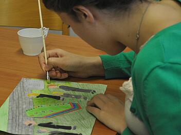 Julia Kranz übermalt die Todeszeichnung mit Wasser. Dadurch leuchten die Farben noch besser.