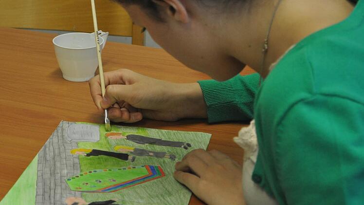 Julia Kranz übermalt die Todeszeichnung mit Wasser. Dadurch leuchten die Farben noch besser.
