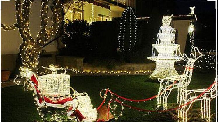 In festlichem Wei&szlig; erstrahlen Brunnen und der Schlitten des Weihnachtsmannes mit Rentieren im Garten von  Familie Die&szlig;enbacher.