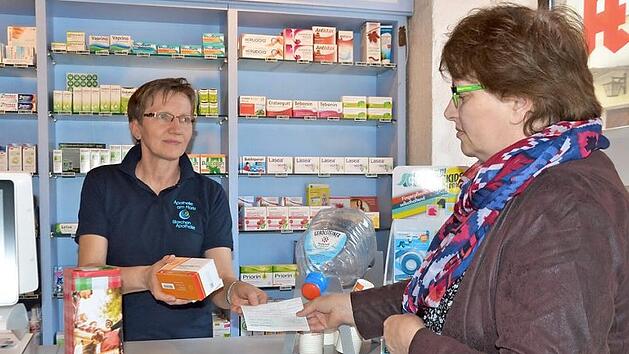 Apothekerin Olga Merdian spricht russisch und hat Hasan stets seine Medikamente gegen Diabetes ausgehändigt. Uschi Schmidt (rechts) löst ein Rezept ein und möchte die Arznei nach Kasachstan schicken. Inzwischen wurden Spendendosen (vorne links) aufgestellt.  Foto: Bernhard Panzer