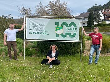 Die Vorsitzenden des SV Ramsthal Jan Gawlik (von links), Anja Langbroek und Udo Schaub vor einem Plakat, das auf das Jubiläum hinweist.