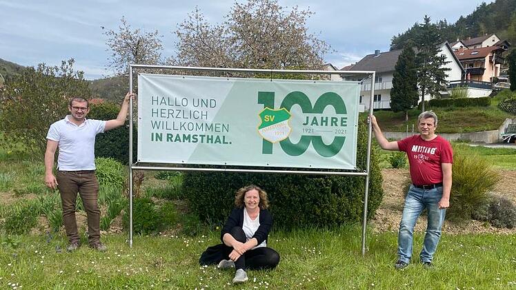 Die Vorsitzenden des SV Ramsthal Jan Gawlik (von links), Anja Langbroek und Udo Schaub vor einem Plakat, das auf das Jubiläum hinweist.