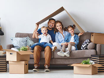 happy family mother father and children move to new apartment and unpack boxes