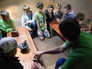 Die Kinder versuchen es selbst in Handarbeit, das Korn zu Mehl zu mahlen. Foto: Regina Rinke