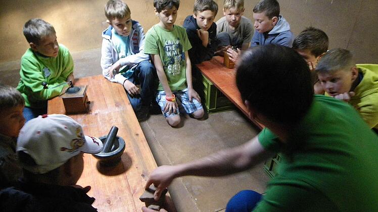 Die Kinder versuchen es selbst in Handarbeit, das Korn zu Mehl zu mahlen. Foto: Regina Rinke