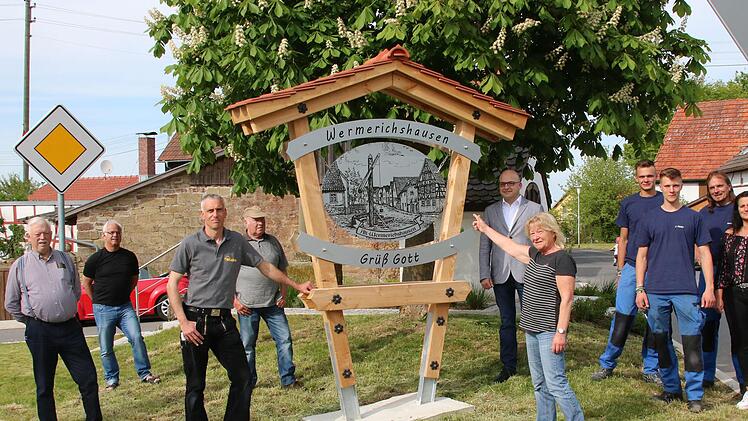 Begrüßungstafeln aus Holz und Metall stehen seit Anfang April an den Ortseingängen von Wermerichshausen. Die Initiative ging von Michael Weigand (3. von links) und Anton Röder (2. von rechts) aus. Auch Bürgermeister Michael Kastl (rechts neben der Tafel) und die bisherige Ortssprecherin Ulla Müller (daneben) waren dabei, als die Tafeln, hier die am Ortsausgang nach Weichtungen, vorgestellt wurden. Foto: Dieter Britz