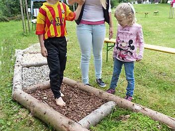 Mit verbundenen Augen wird David Stöcker über den Barfußpfad geführt. Helferin Tanja Schlee und seine kleine Schwester Sarah schauen interessiert zu. Foto: Jürgen Schlee