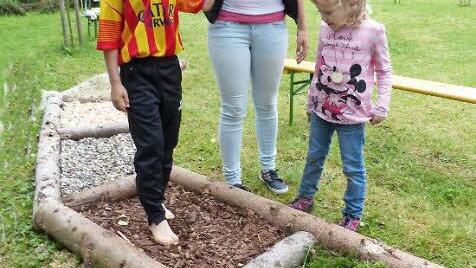 Mit verbundenen Augen wird David Stöcker über den Barfußpfad geführt. Helferin Tanja Schlee und seine kleine Schwester Sarah schauen interessiert zu. Foto: Jürgen Schlee